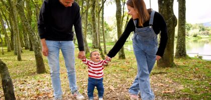 A joyful family enjoys a walk under lush green trees in the park.